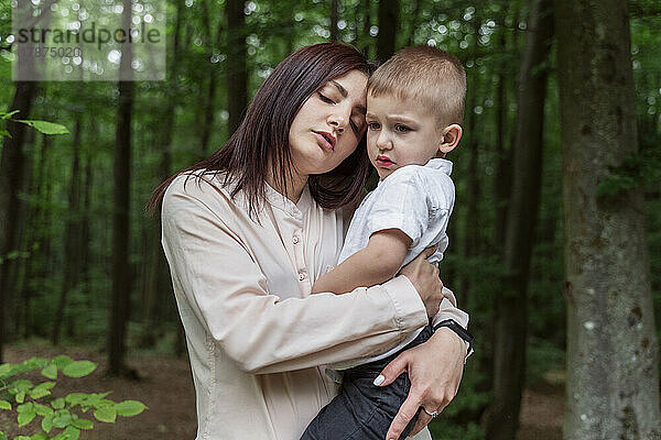 Mutter mit geschlossenen Augen trägt Sohn im Wald