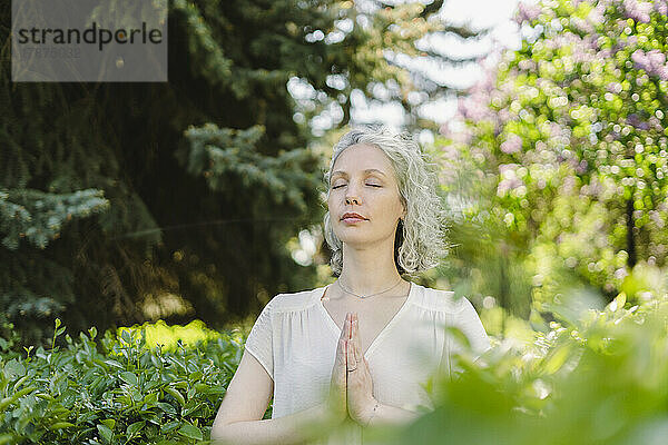 Frau mit geschlossenen Augen meditiert im Park