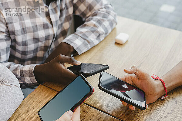 Gemischtrassige Freunde mit Smartphones am Tisch im Café