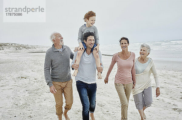 Glückliches Paar verbringt schöne Zeit am Strand mit Sohn und Großeltern