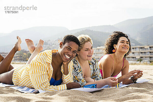 Fröhliche  gemischtrassige Freunde  die sich im Urlaub am Strand hinlegen