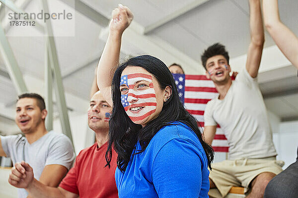 Frau mit aufgemalter amerikanischer Flagge jubelt mit Freunden im Stadion