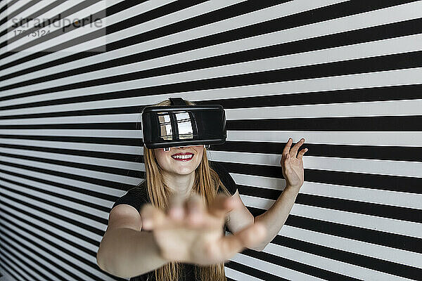 Lächelndes Teenager-Mädchen gestikuliert mit Virtual-Reality-Headset