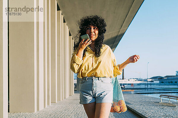 Frau mit Netztasche sendet Voicemail über Smartphone