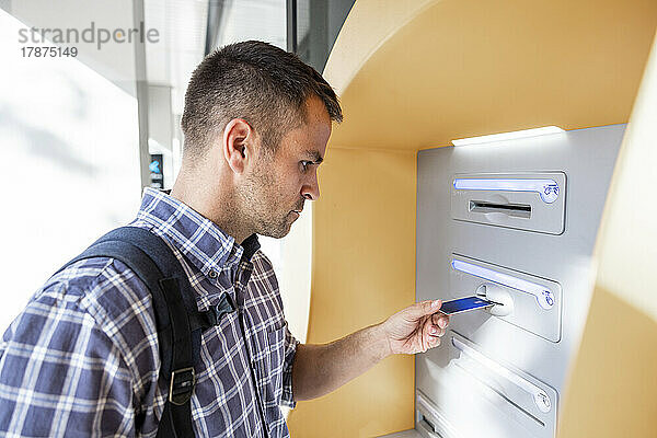 Reifer Mann steckt Kreditkarte in Geldautomaten