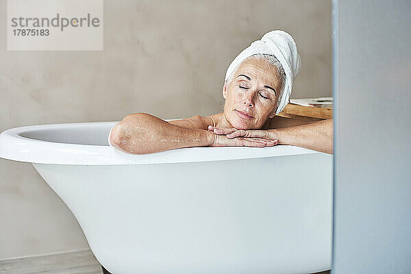 Woman with eyes closed relaxing in bathtub