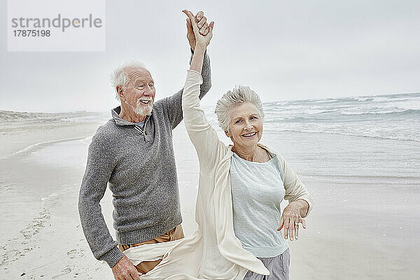 Glückliches älteres Paar tanzt am Strand