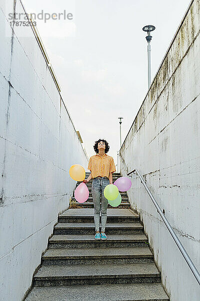 Frau mit Luftballons steht auf Stufen