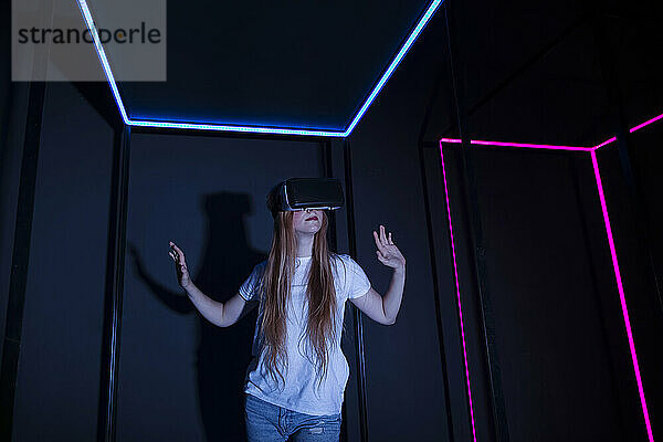 Teenage girl with virtual reality headset by illuminated neon lights