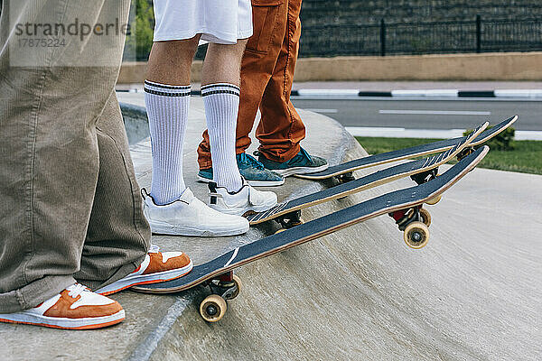 Beine von Freunden mit Skateboards im Park