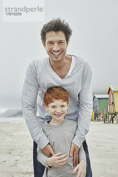 Laughing father and son standing on windy beach