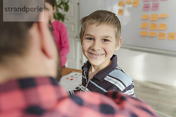 Lächelnder Junge vor dem Lehrer zu Hause