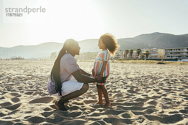 Glücklicher Mann mit Tochter am Strand an einem sonnigen Tag