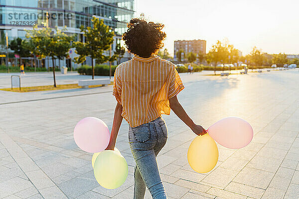 Frau mit Luftballons läuft auf Fußweg