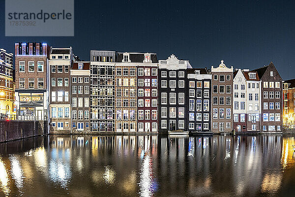Niederlande  Nordholland  Amsterdam  Langzeitbelichtung des Damrak-Kanals bei Nacht mit Reihenhäusern im Hintergrund