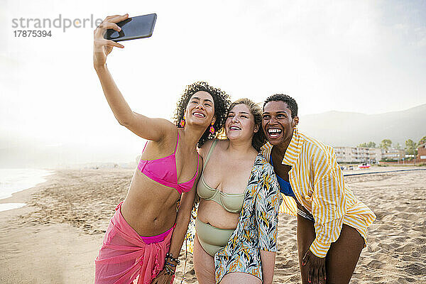 Gemischtrassige Freunde machen am Strand ein Selfie mit dem Smartphone