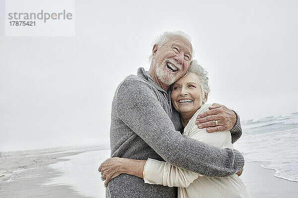 Lachendes älteres Paar  das sich am Meer umarmt