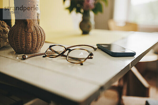 Brillen und Smartphone liegen zu Hause auf dem Tisch