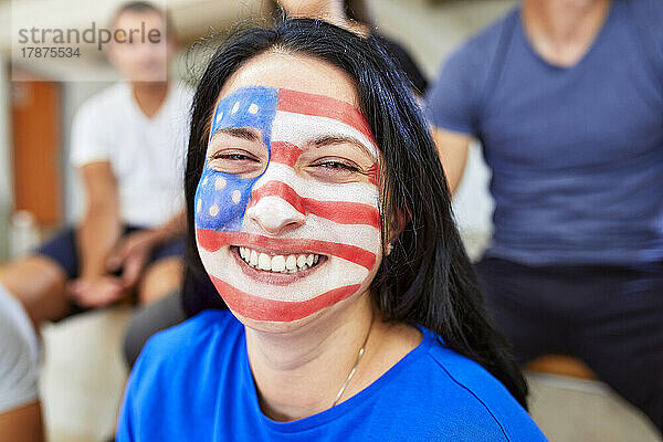 Fröhliche Frau mit amerikanischer Flagge im Gesicht