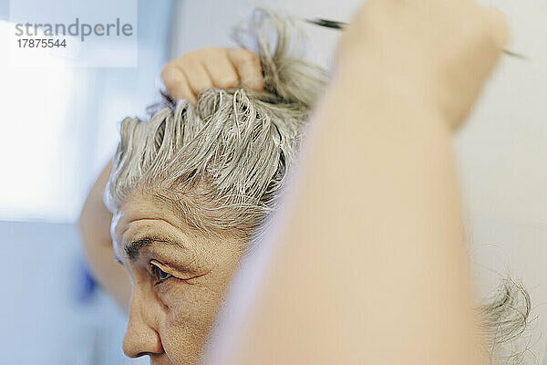 Ältere Frau trägt zu Hause Haarfärbemittel auf