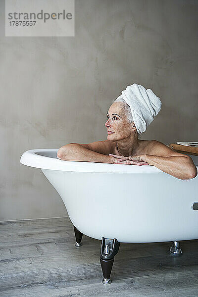 Contemplative woman in bathtub at home