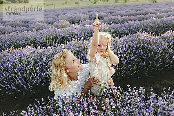 Mother with girl talking on smart phone amidst lavender plants