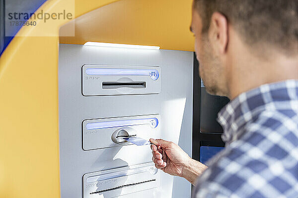 Mann führt Kreditkarte in Geldautomaten ein