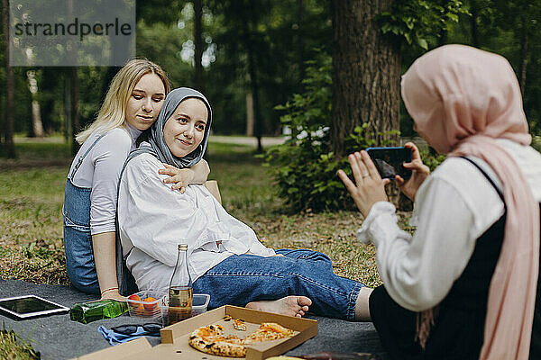 Junge Frau fotografiert Freunde per Smartphone im Park