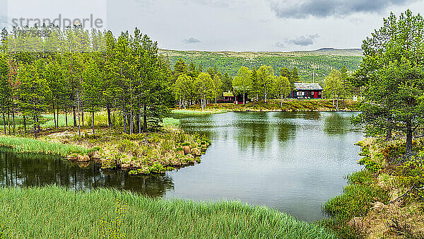 Norwegen  Innlandet  See im Rondane-Nationalpark mit abgelegener Hütte im Hintergrund