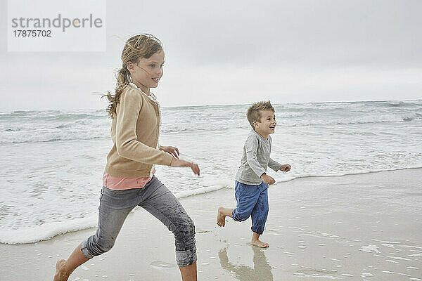 Bruder und Schwester haben Spaß beim Laufen am Strand