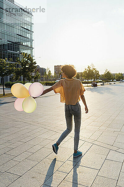 Frau spielt bei Sonnenuntergang mit Luftballons