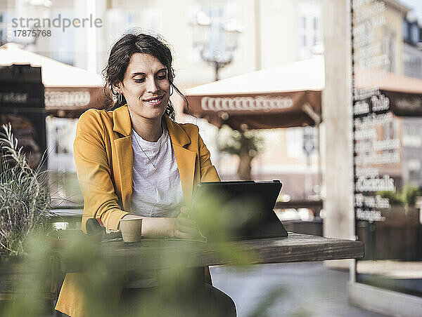 Lächelnde Transgender-Geschäftsfrau benutzt Tablet-PC im Café