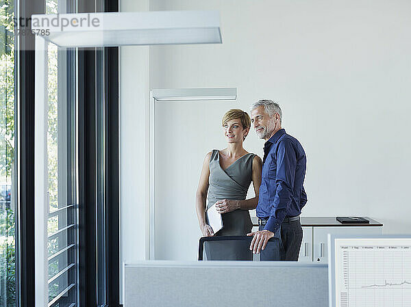 Nachdenkliche Geschäftskollegen schauen durch das Fenster im Büro