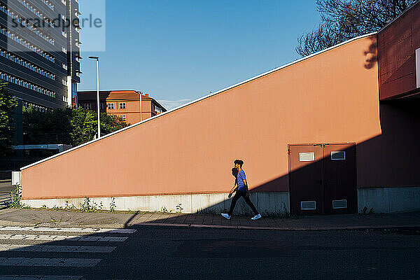 Young man walking by wall in city