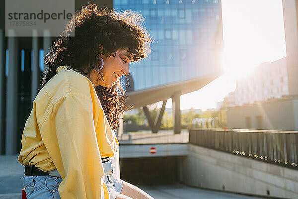 Lächelnde Frau  die an einem sonnigen Tag auf das Gebäude blickt