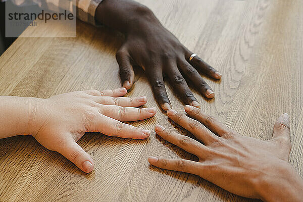 Hands of multiracial friends on table
