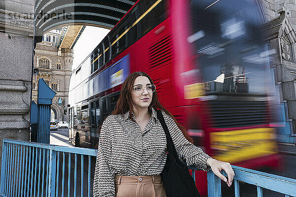 Junge Frau mit Brille steht am Geländer der Tower Bridge  London  England