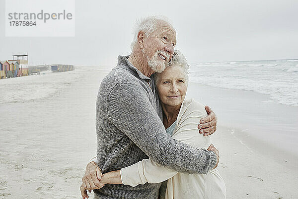 Älteres Paar umarmt sich am Meer