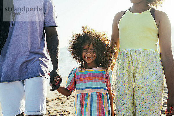Glückliches Mädchen mit Vater und Schwester am Strand