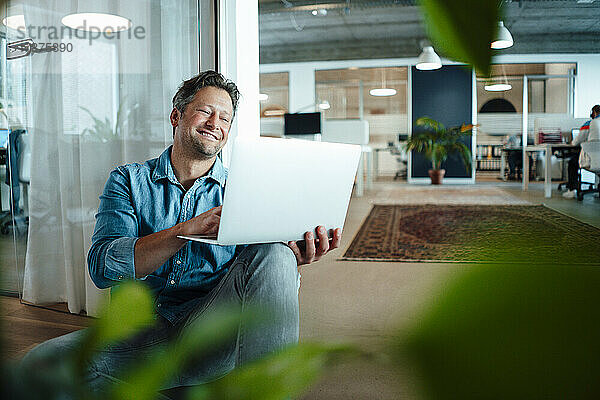 Happy businessman using laptop in office