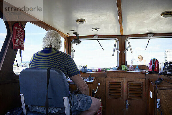 Älterer Mann segelt mit einem Motorboot im Urlaub