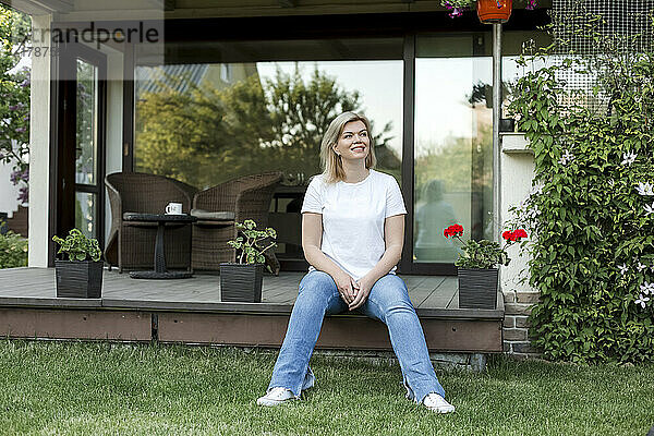 Lächelnde reife Frau sitzt auf der Veranda