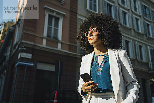Junge Geschäftsfrau mit Mobiltelefon an einem sonnigen Tag
