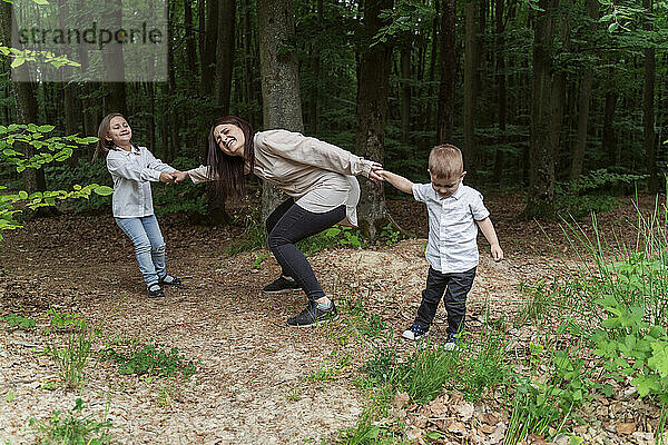 Kinder ziehen Mutter und haben Spaß im Wald