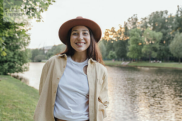 Fröhliche Frau mit Hut am See im Park