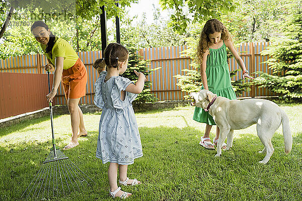 Frau und Mädchen mit Hund im Hinterhof