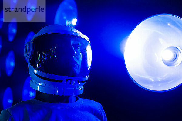 Nachdenkliche Frau mit Weltraumhelm bei blau beleuchtetem Licht