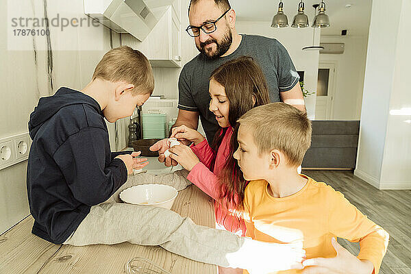 Kinder geben dem Vater in der Küche Eierschalen