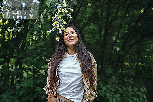 Lächelnde Frau  die vor einem Baum steht