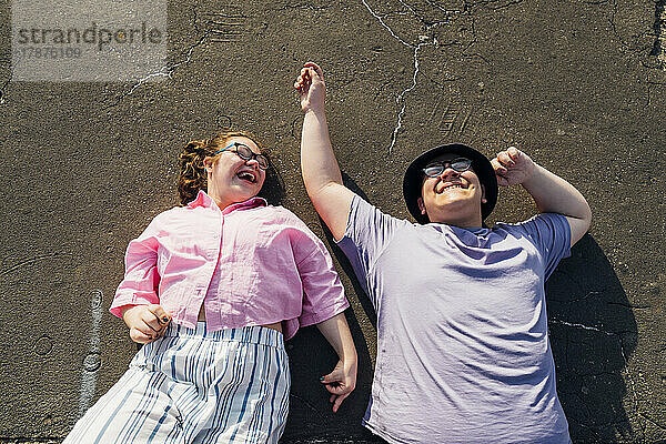 Brother and sister laughing and lying on street